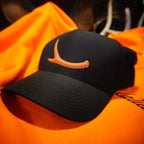 Black cap with orange logo on an orange shirt